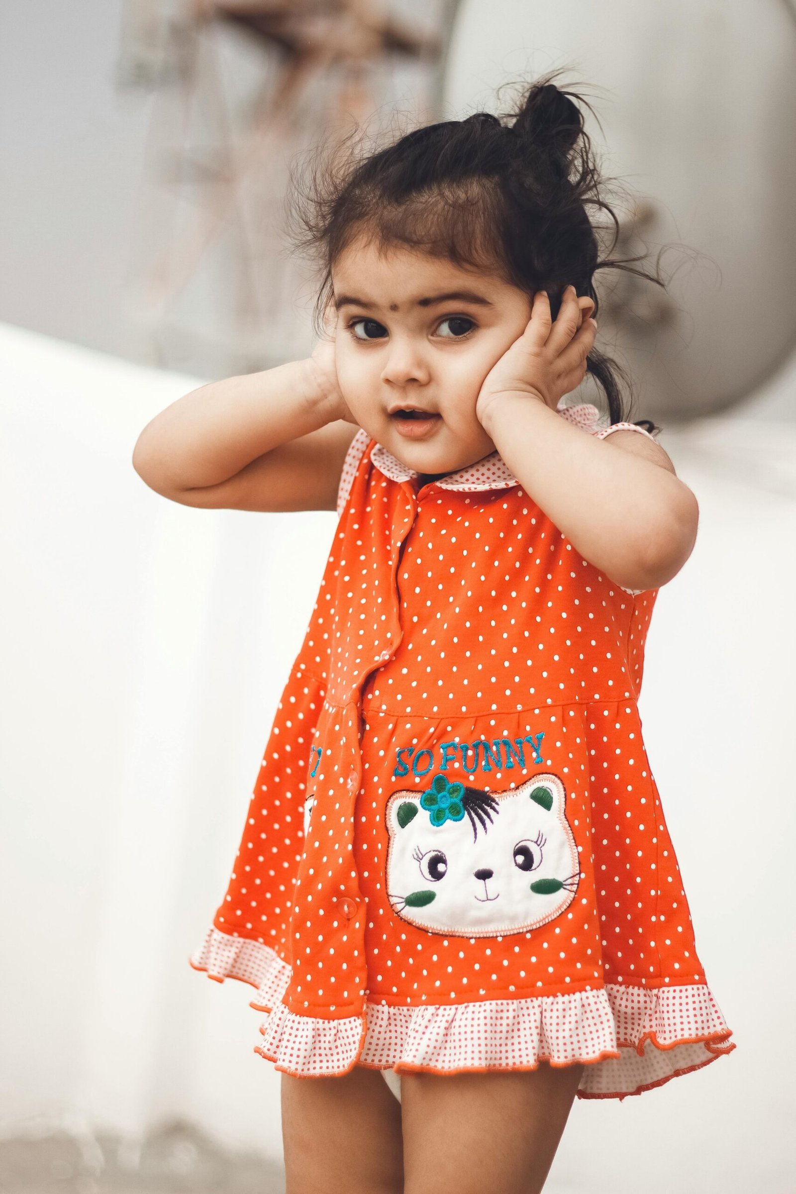 Cute young girl with playful expression and polka dot dress outdoors in New Delhi.